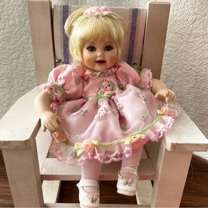 Marie Osmond sitting porcelain doll with blonde hair.